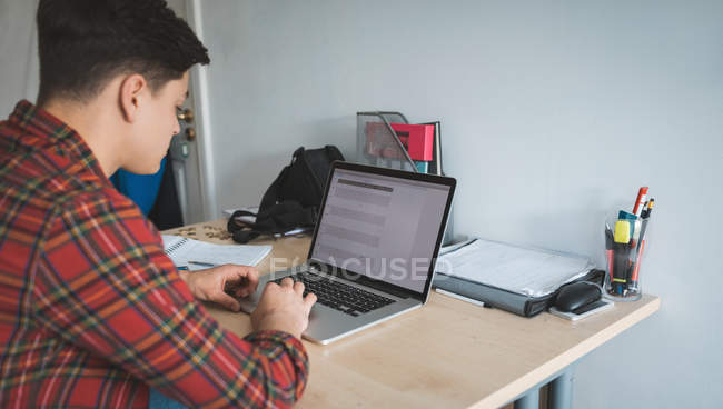 Молодий чоловік працює з ноутбуком за столом вдома . — стокове фото