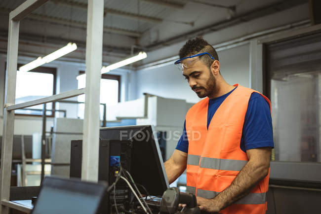 Работник-мужчина, работающий на компьютере на заводе — стоковое фото