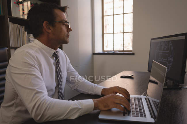 Бізнесмен, використовуючи ноутбук за столом в офісі, вид збоку . — стокове фото