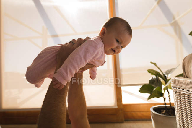 Primo piano di padre mani sollevamento bambino a casa . — Foto stock