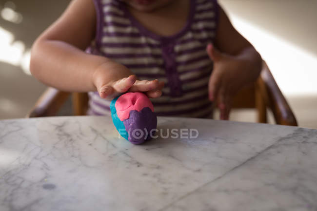Seção média da menina criança brincando com argila em casa . — Fotografia de Stock