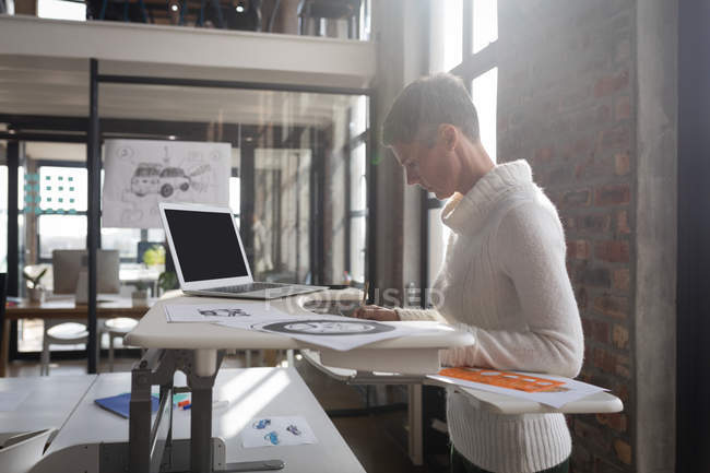 Businesswoman looking at sketches in office. — Stock Photo