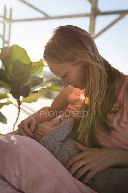 Mãe amamentando bebê menino na luz solar . — Fotografia de Stock