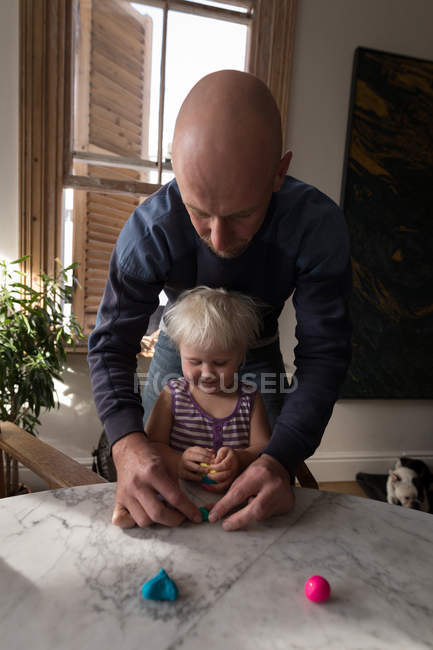 Vater und Kleinkind spielen im heimischen Wohnzimmer mit Ton. — Stockfoto