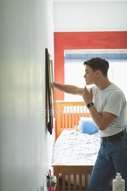 Young man applying face cream in front of mirror in bedroom at home. — Stock Photo