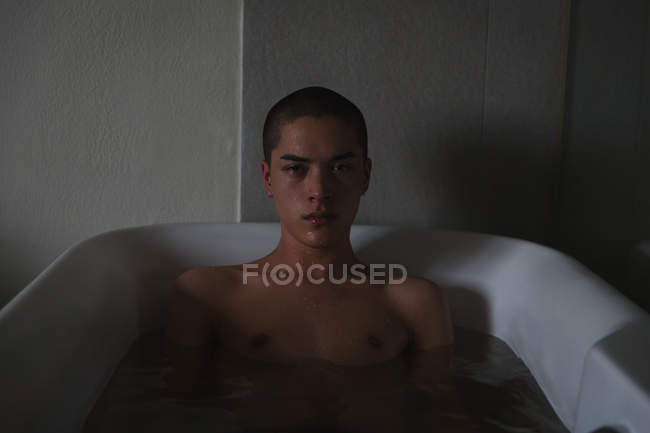 Porträt eines jungen Mannes, der es sich in Badewanne im Badezimmer gemütlich macht — Stockfoto