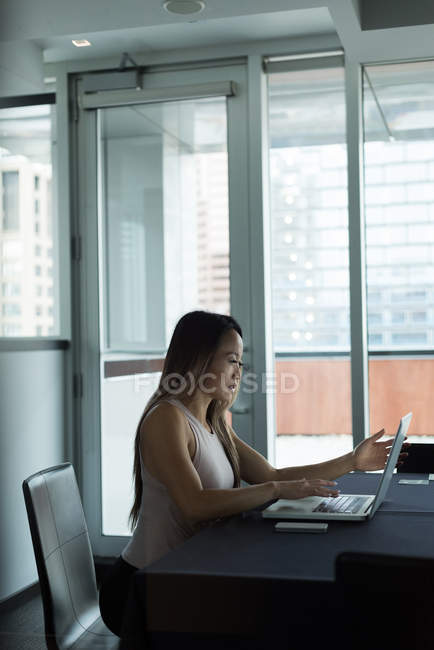 Asiatico businesswoman seduta da solo lavoro su suo laptop in il ufficio — Foto stock