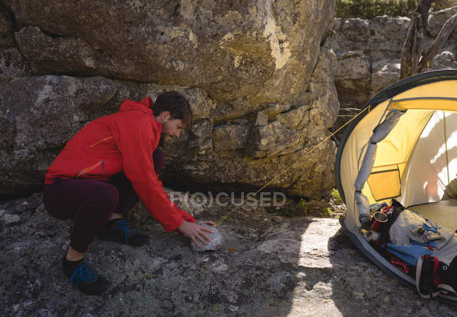 Hiker building up tent in mountain on a sunny day — Stock Photo