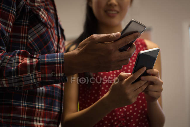 Бізнес-колеги використовують мобільний телефон в офісі — стокове фото
