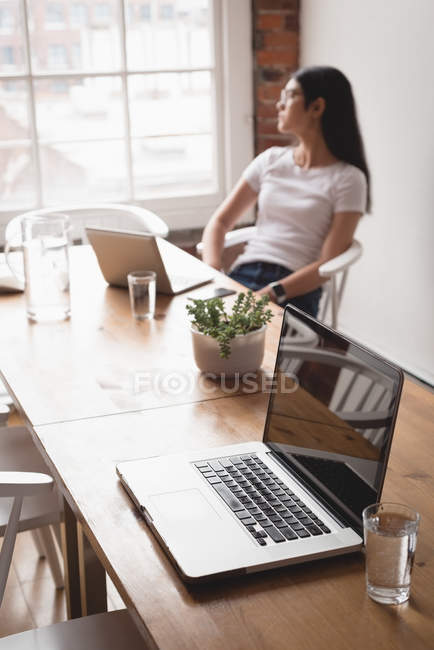 Pensativo ejecutivo femenino sentado en la silla en la oficina creativa - foto de stock