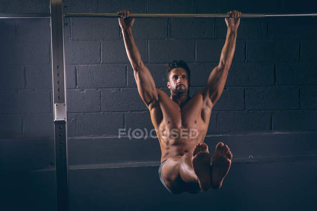 Homem musculoso exercitando-se no bar pull-up no estúdio de fitness — Fotografia de Stock