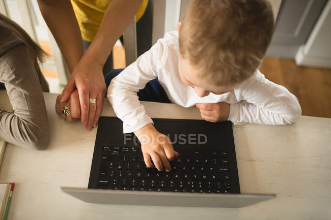 Primo piano della madre che insegna al figlio a usare il computer portatile a casa — Foto stock