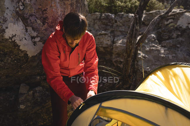 Турист строит палатку в горах в солнечный день — стоковое фото