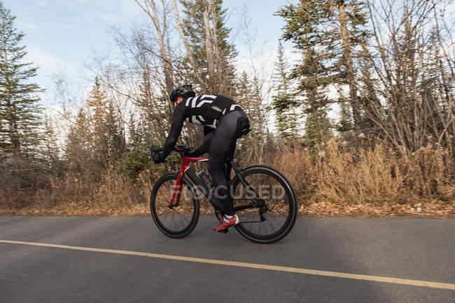 Biker andar de bicicleta de montanha na estrada em um dia ensolarado — Fotografia de Stock