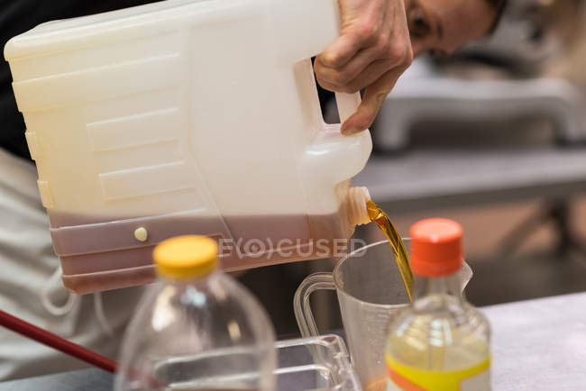 Nahaufnahme eines Küchenchefs, der Speiseöl in einen Behälter gießt — Stockfoto