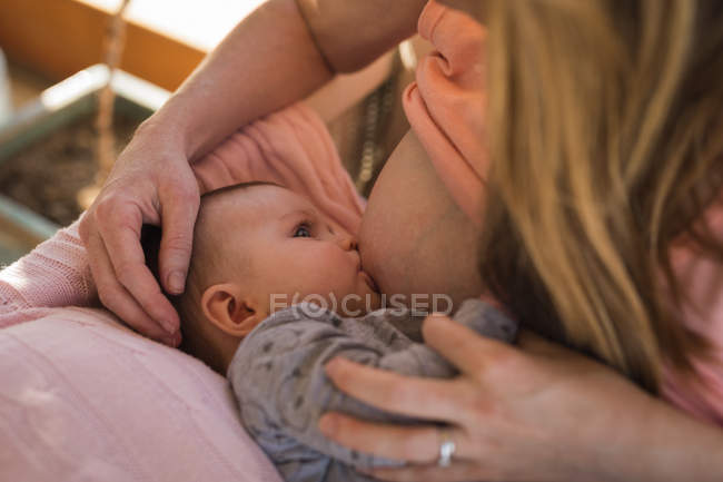 Close-up of mother breastfeeding baby boy indoors. — Stock Photo