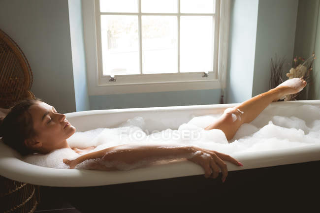 Femme relaxant dans le bain avec de la mousse à la maison . — Photo de stock