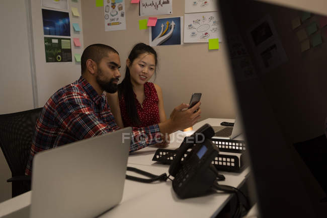 Business colleagues using mobile phone at desk in office — Stock Photo