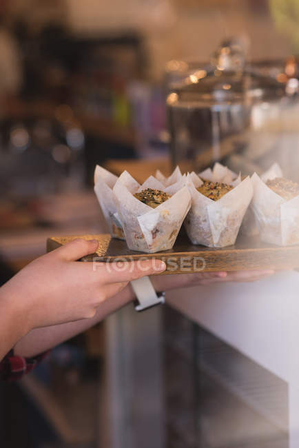 Close-up de garçonete segurando muffins na bandeja no balcão — Fotografia de Stock