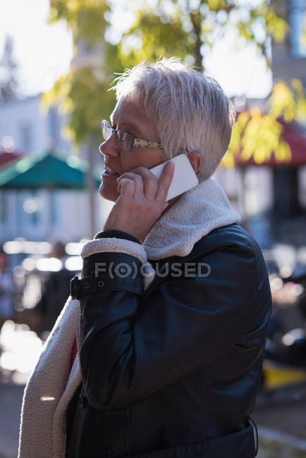 Vista lateral de la mujer mayor hablando en el teléfono móvil - foto de stock