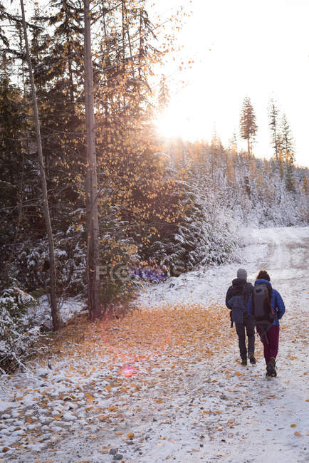 Caminante pareja caminando a través de la nieve durante el otoño - foto de stock