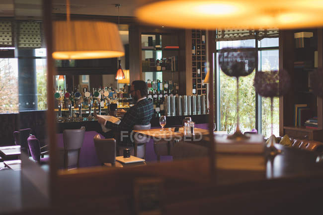 Бизнесмен проверяет документы, выпивая виски в баре — стоковое фото