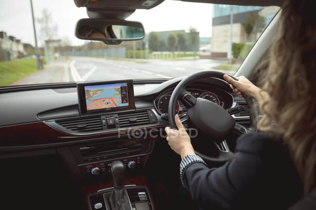 Rear view of female executive driving car on the street — Stock Photo