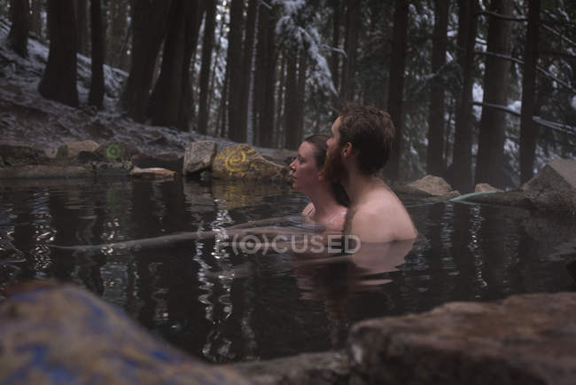 Thoughtful couple relaxing in hot spring during winter — Stock Photo