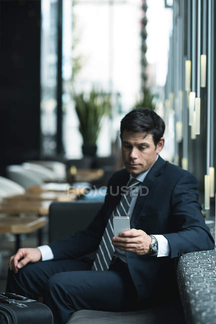 Empresário usando telefone celular no lobby do hotel — Fotografia de Stock