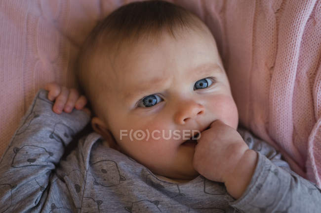 Close-up of baby boy with hand in mouth. — Stock Photo