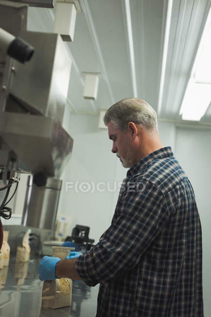 El hombre refina grano en la máquina en fábrica - foto de stock
