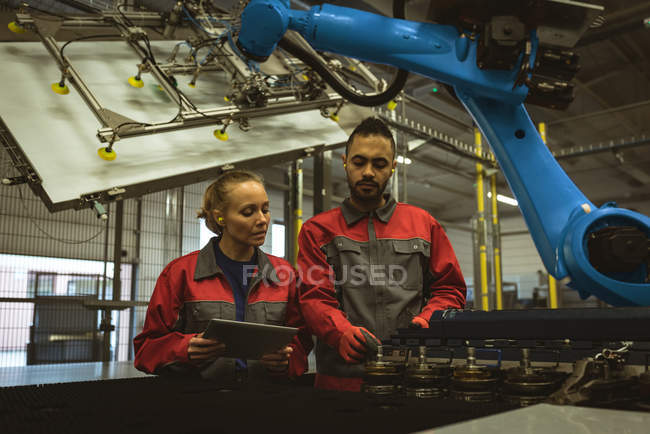 Zwei Arbeiter diskutieren in Fabrik über digitales Tablet — Stockfoto