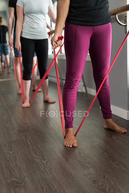 Faible proportion de femmes faisant de l'exercice avec des bandes de résistance dans un studio de fitness . — Photo de stock