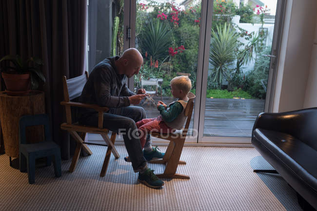 Pai ensinando filho sobre tricô com pino e fio em casa . — Fotografia de Stock