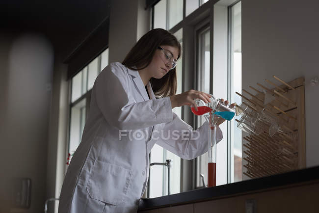 Дівчинка-підліток експериментує з хімічним розчином в лабораторії — стокове фото