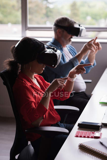 Colleagues experiencing virtual reality headset on desk at creative office — Stock Photo