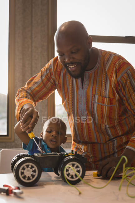 Батько і син ремонтують електромобіль з викруткою вдома . — стокове фото