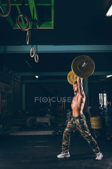 Homem musculoso exercitando com barbell no estúdio de fitness — Fotografia de Stock