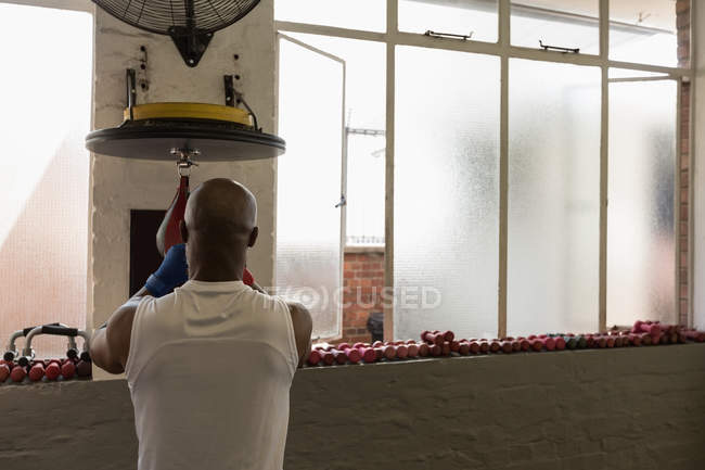 Vue arrière du sac de vitesse de poinçonnage homme dans le studio de fitness . — Photo de stock