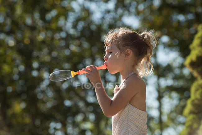 Мила дівчина грає з бульбашковою паличкою в парку — стокове фото