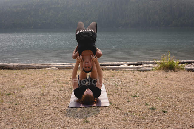 Fittes Paar, das in der Morgendämmerung Akro-Yoga in einem sattgrünen Boden praktiziert — Stockfoto