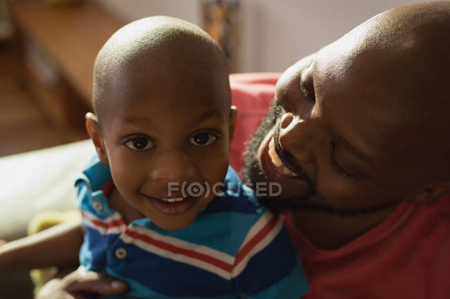 Padre e figlio sorridono in salotto a casa . — Foto stock