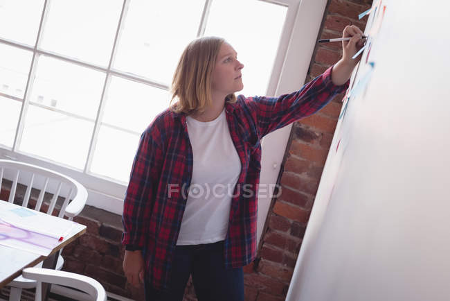 Escritura ejecutiva femenina en notas adhesivas en la oficina creativa - foto de stock