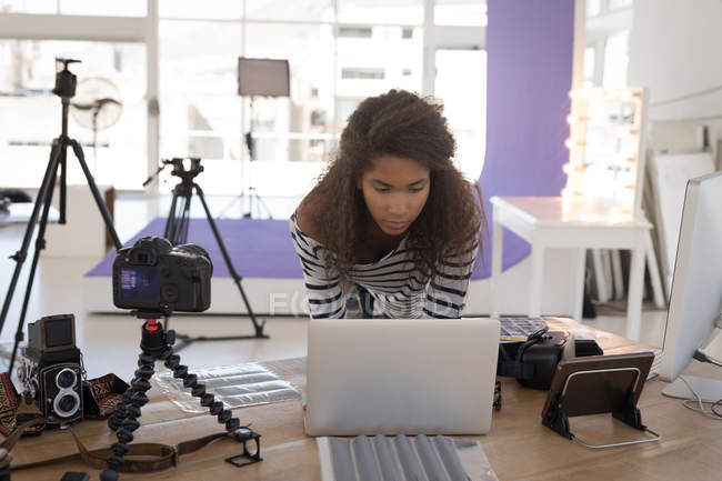 Фотограф використовує ноутбук за столом у фотостудії — стокове фото