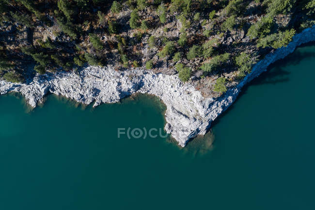 Overhead view of rocky cliff and trees along the turquoise sea — Stock Photo