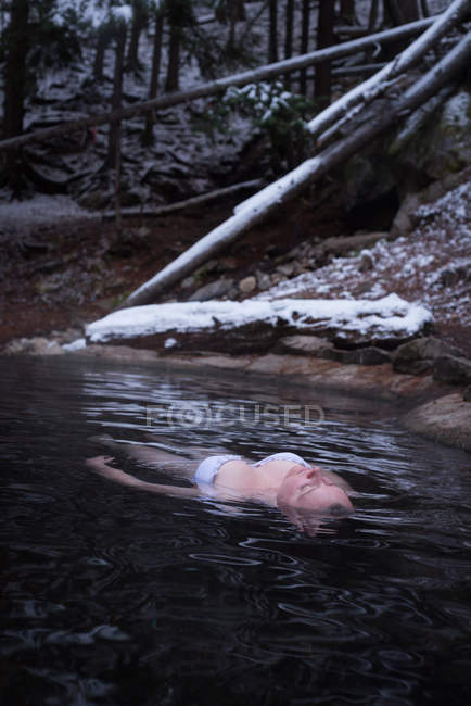 Attractive woman relaxing in hot spring during winter — Stock Photo