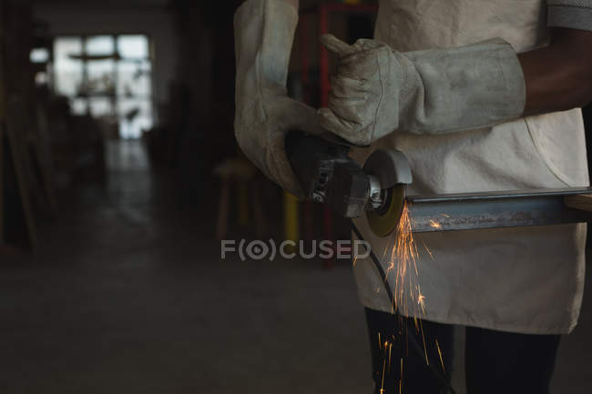 Découpage métal menuisier avec scie électrique en atelier — Photo de stock