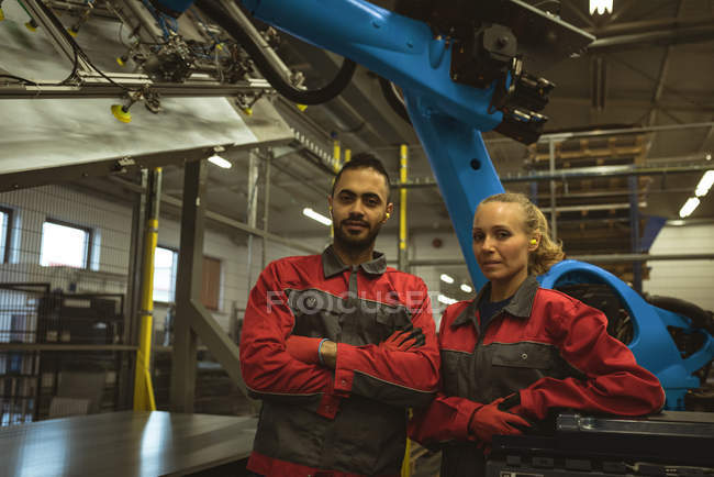 Retrato de trabalhador masculino e feminino em pé junto com os braços cruzados na fábrica — Fotografia de Stock