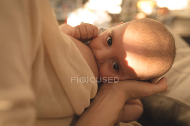 Крупный план молодой матери, кормящей грудью своего ребенка дома — стоковое фото