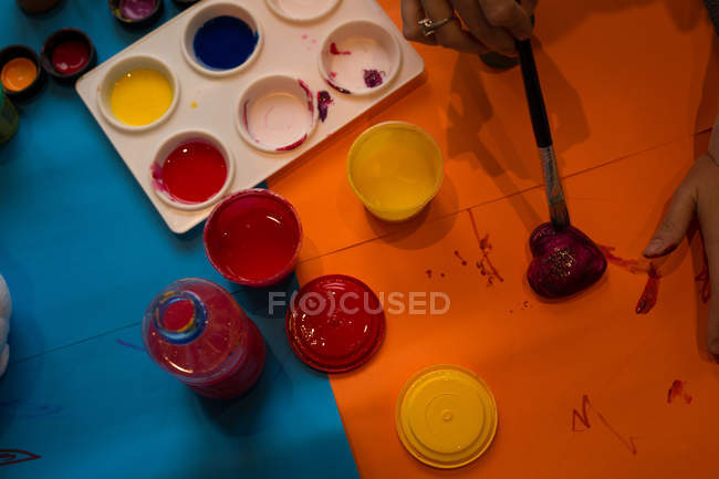 Close-up of girl painting a heart shaped toy — Stock Photo